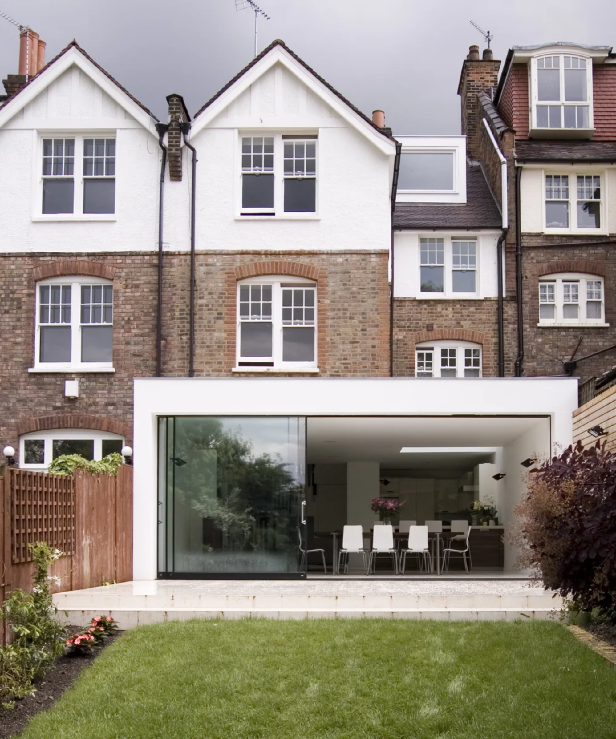 terraced house with white rendered loft conversion, white rendered single storey extension and white render to third storey of house with brick below