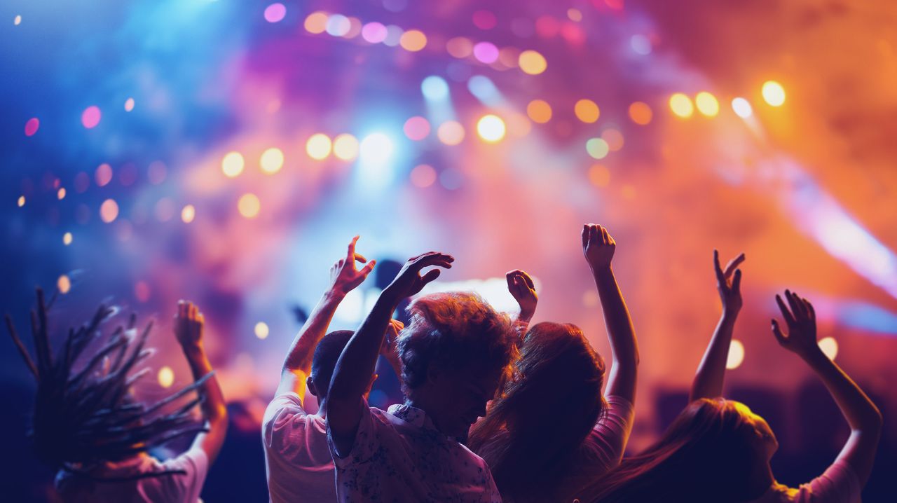 People dancing and jumping at a colourful concert.