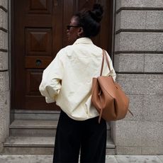 liv wears white jacket, black pants, and oversized brown leather tote