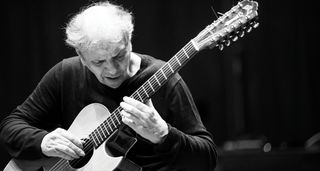 A black-and-white portrait of Ralph Towner with his acoustic guitar