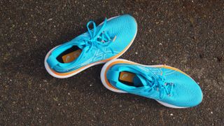 The ASICS Gel-Nimbus 25 in bright blue pictured on a concrete surface.