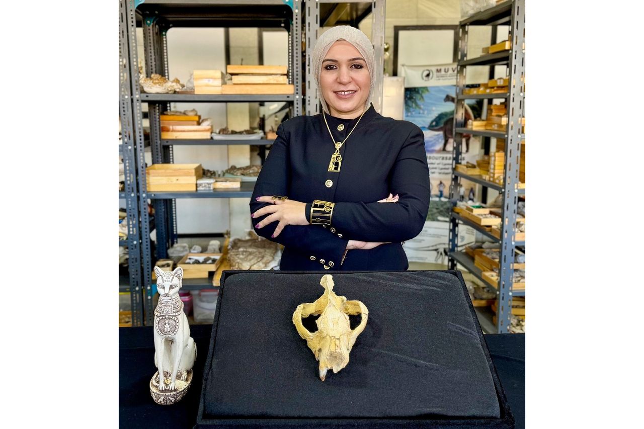 A woman poses in front of a large skull