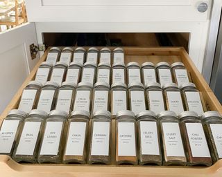 Organized spice drawer with matching labels on glass jars