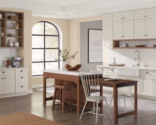 open plan kitchen with white cabinets, beige wall and wooden island unit