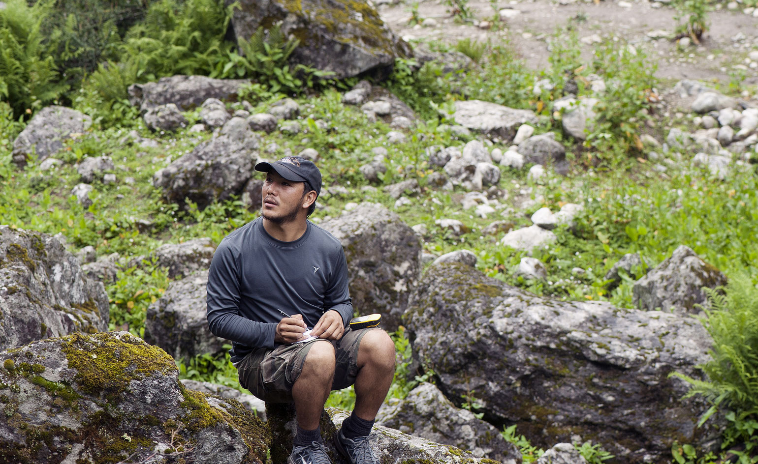 Man sat on a hill surrounded by rocks