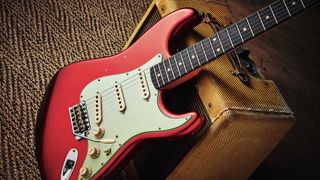 Red Fender Stratocaster leaning against a vintage amp
