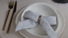 a napkin folded into a bow on plates with gold cutlery