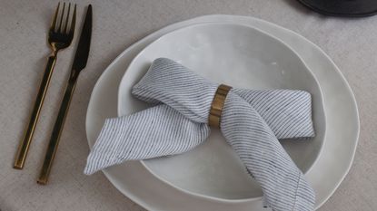 a napkin folded into a bow on plates with gold cutlery