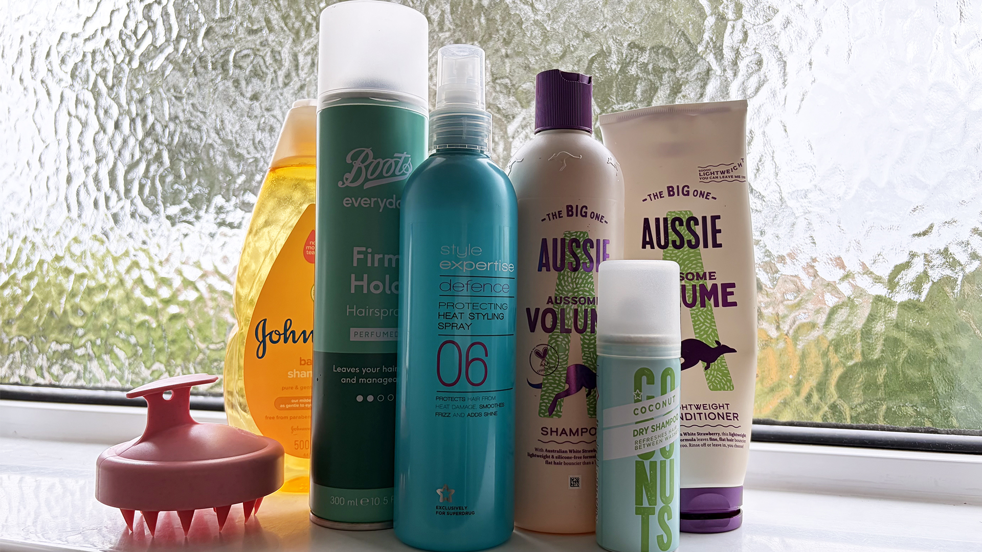 Bottles of shampoo, conditioner, hair spray and dry shampoo on a shelf in a bathroom