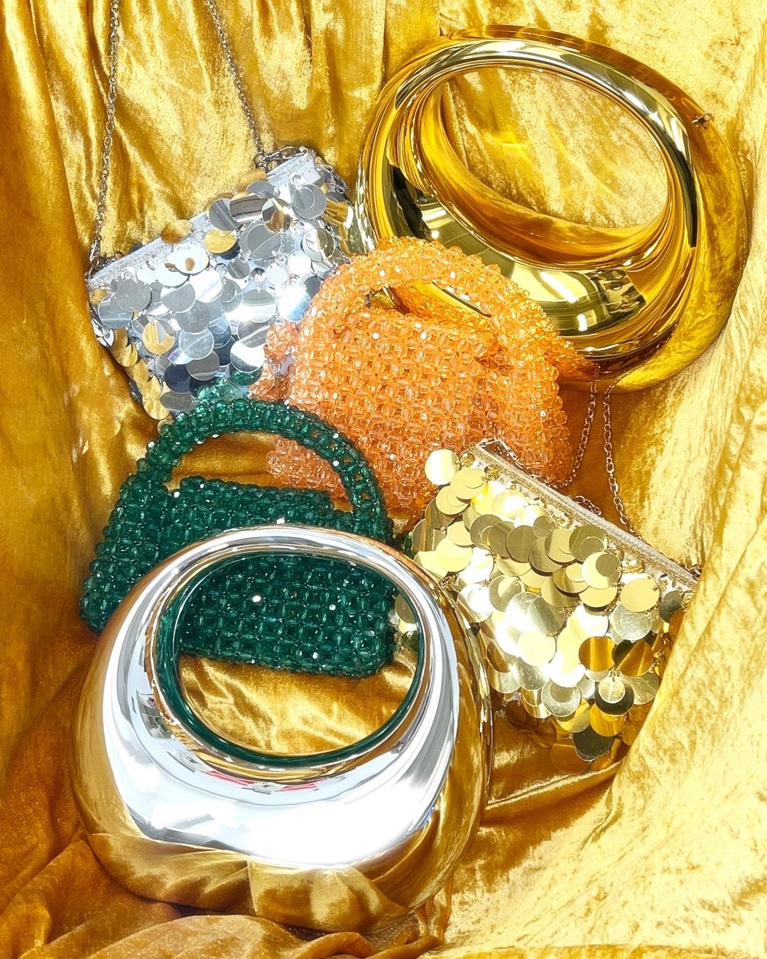 silver and gold bags laid on gold fabric