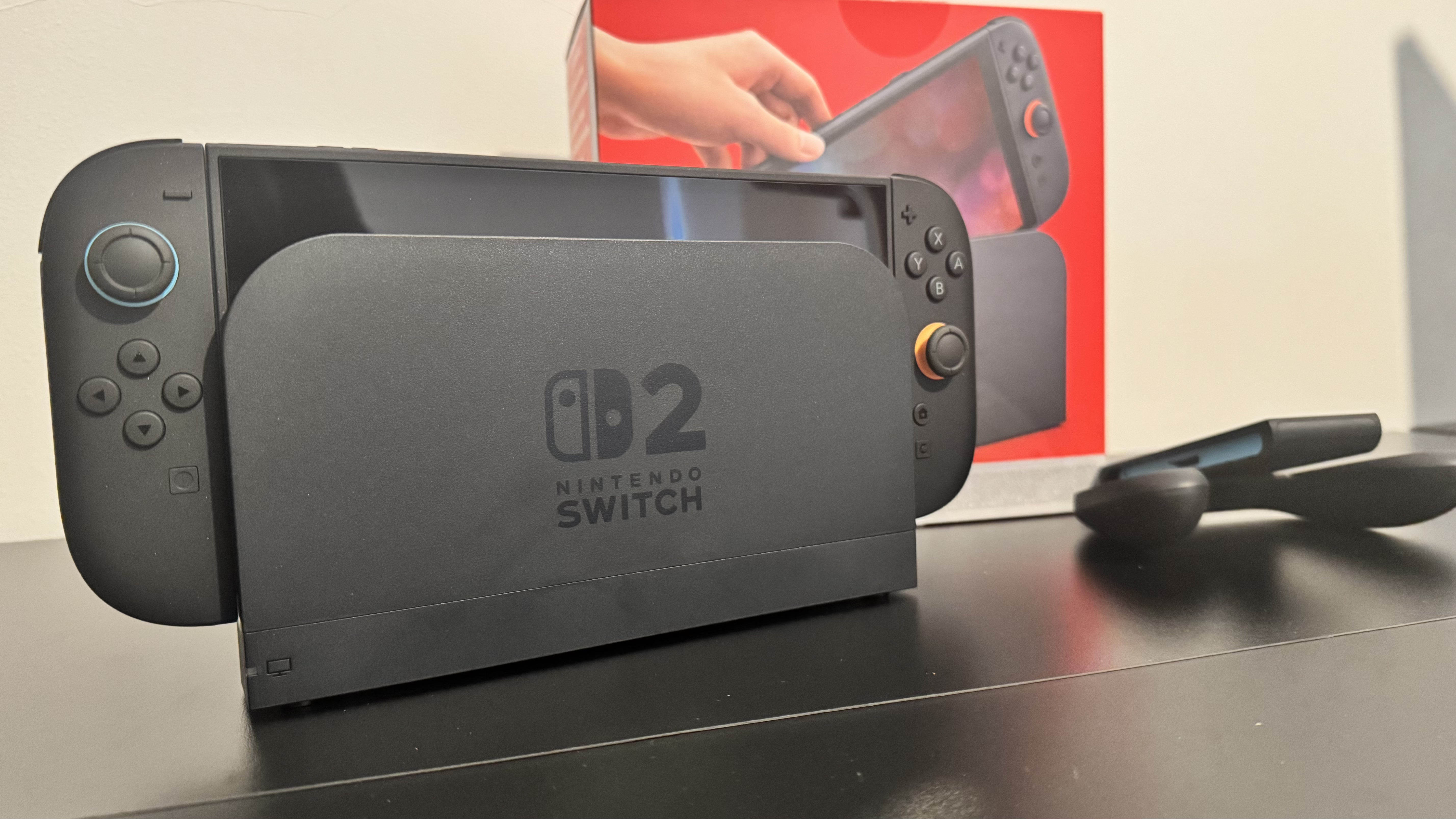 A picture of Nintendo Switch 2 dock with the console inside, and the Switch 2 box behind it