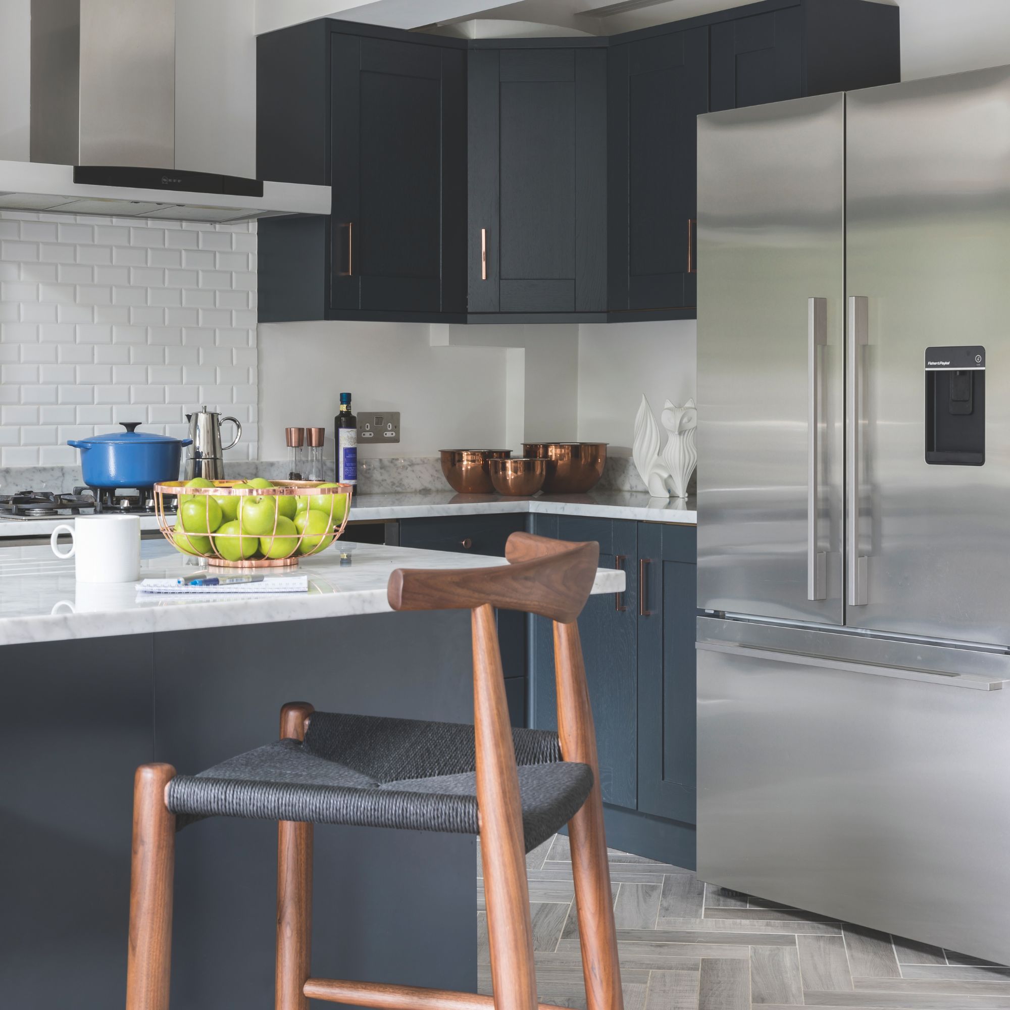 white tiled kitchen with blue cabinets and a matching island, and a large fridge-freezer