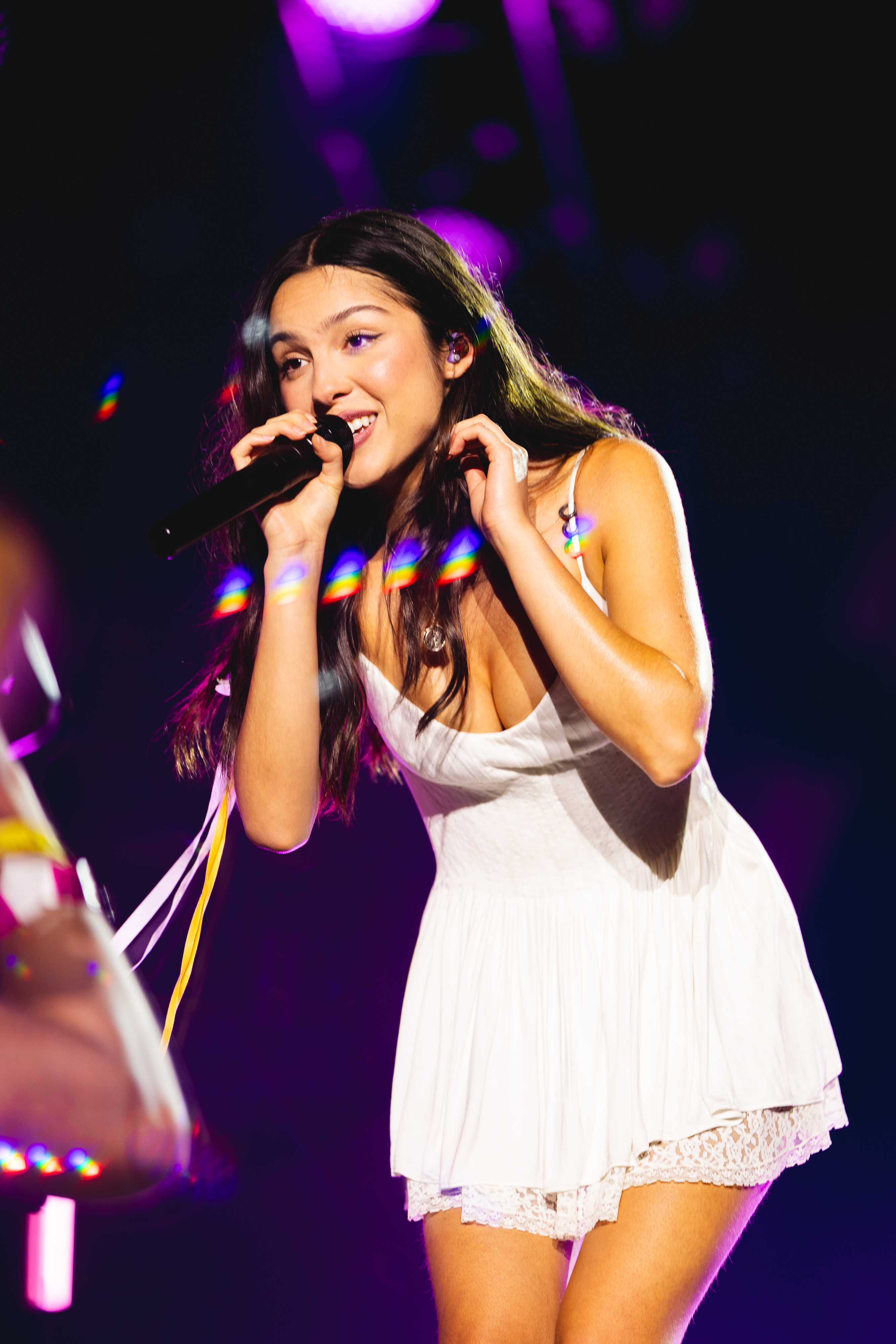 Olivia Rodrigo wears a white lacy dress with a white daisy in her hair to perform at Daisy Chain Fields