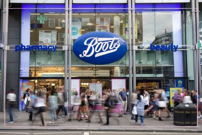 The front of a Boots store with blurred figures walking past