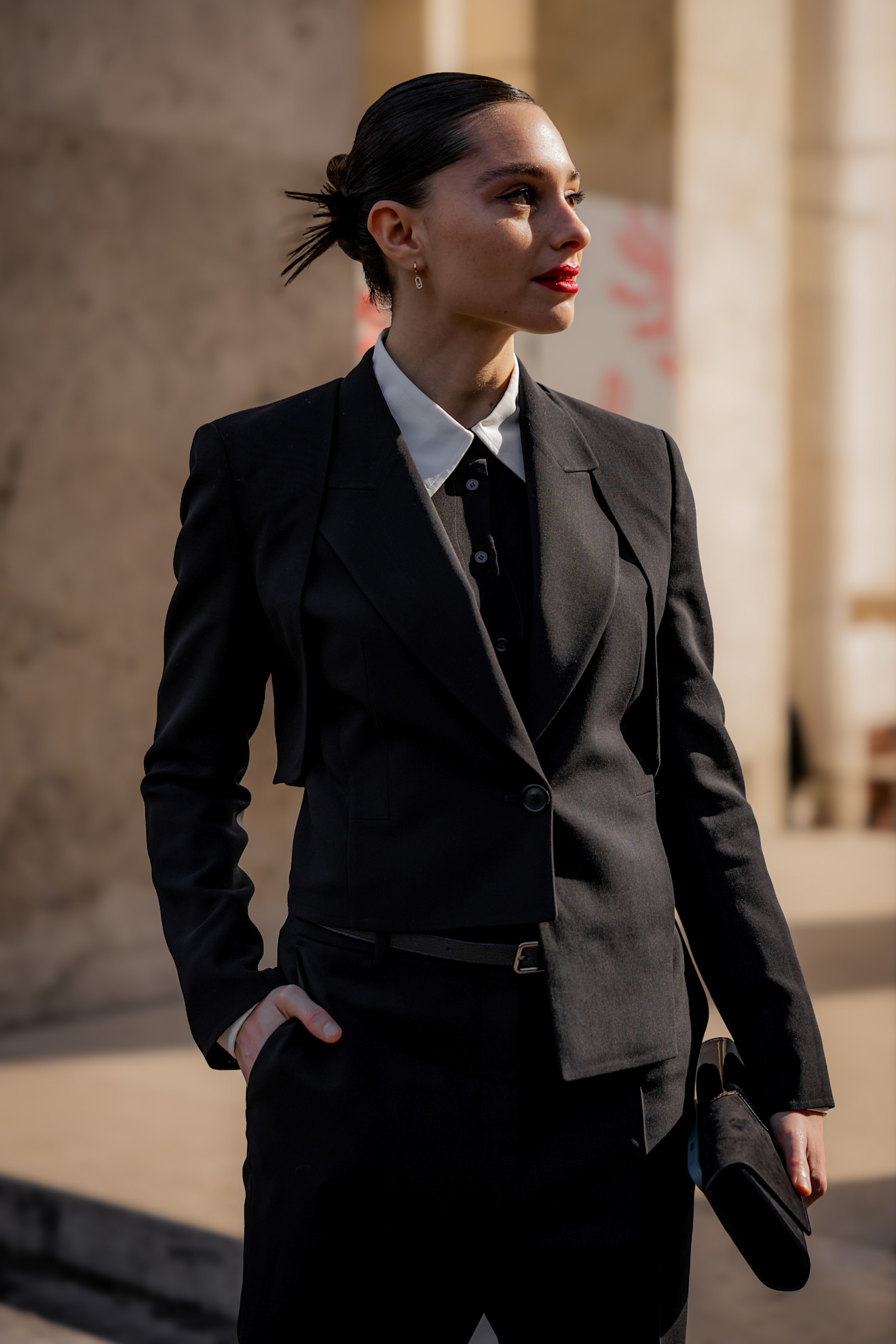 a woman in a black suit, tie, with her hair in a bun