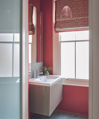 red walls in bathroom with patterned blinds and rectangular sink unit