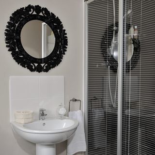 bathroom with wash basin with modern black tiles and the ornate rococo style mirror
