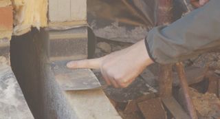 A hand pointing at a damp proof course