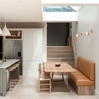 open plan kitchen diner with leather banquette seating and a kitchen island with bar stools, skylight and a fridge freezer