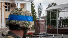 A Ukrainian soldier looks at a damaged statue of Vladimir Lenin in the Russian city of Sudzha.