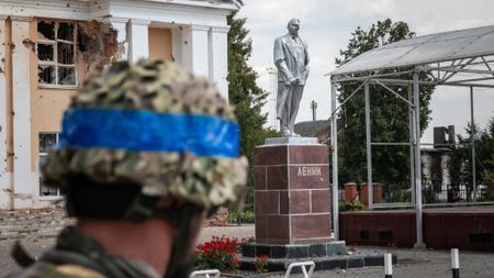 A Ukrainian soldier looks at a damaged statue of Vladimir Lenin in the Russian city of Sudzha.