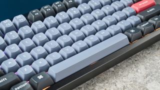 The Keychron Q6 on a stone surface with a blue wall in the background.