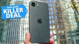 iPhone 16e held in the hand with killer deal badge nearby.