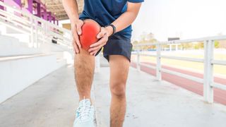 A runner holding injured knee