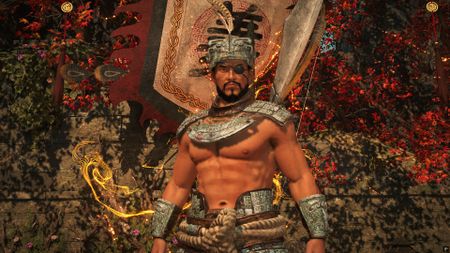 The player character, shirtless with armor only on their shoulders, stands in front of a banner in Wo Long 2: Wings of Ember
