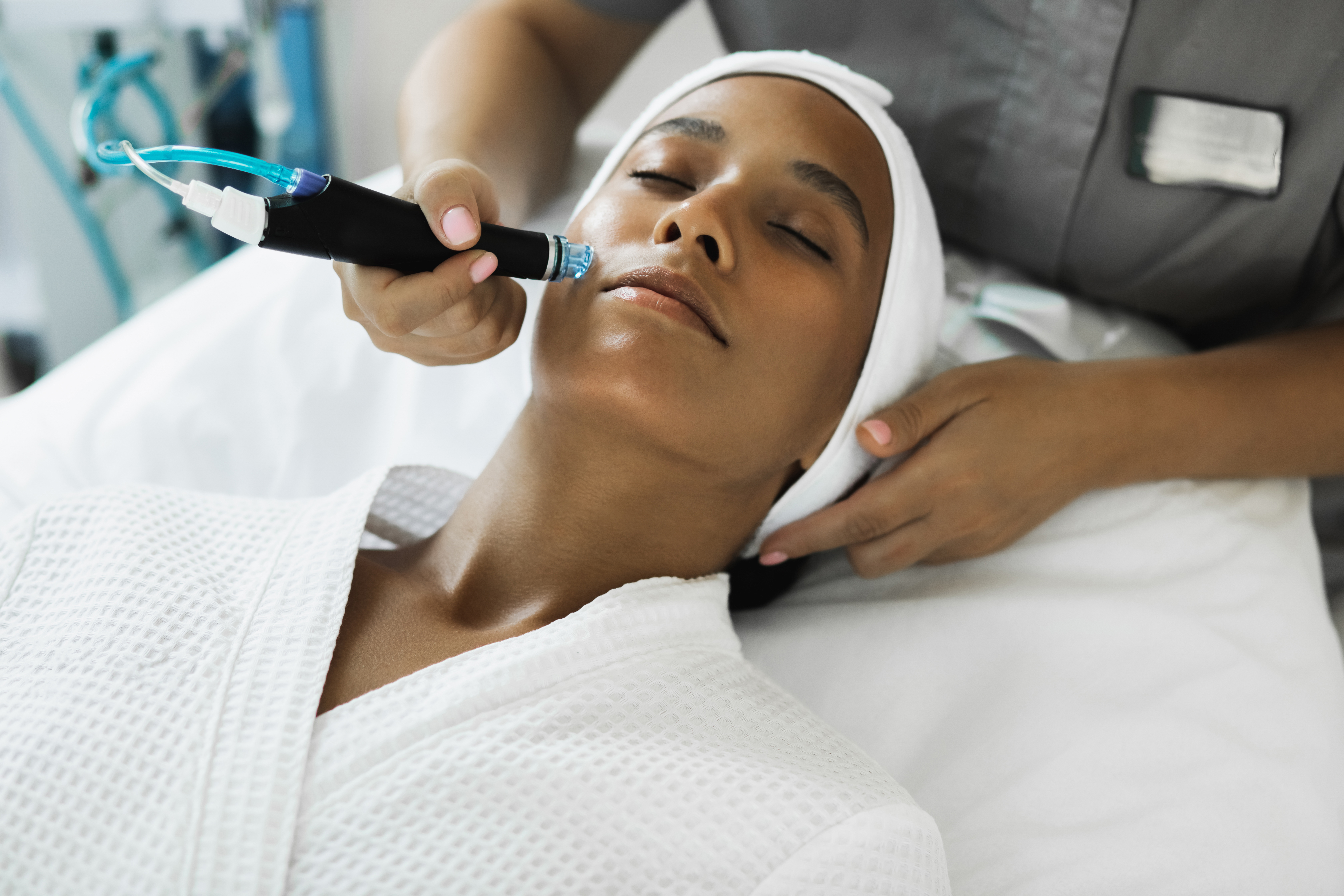 a woman in a white robe laying on a table getting a laser skincare treatment