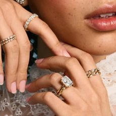 A close up of a woman wearing a variety of diamond gold rings from Frank Darling.