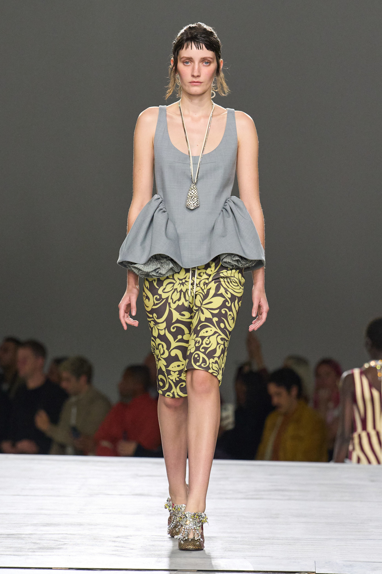 a model at Dries Van Noten Spring 2026 wearing brown and yellow board shorts with a gray top