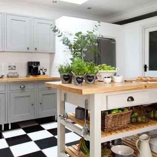 White and grey kitchen with portable island and chequered floor