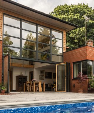 composite wood and aluminium bi-fold doors on brick house with large glass window above