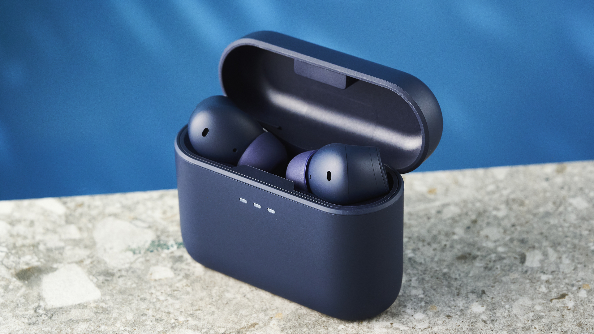 the cambridge audio a100 se earbuds on a blue tom's guide background with a stone-coloured table underneath