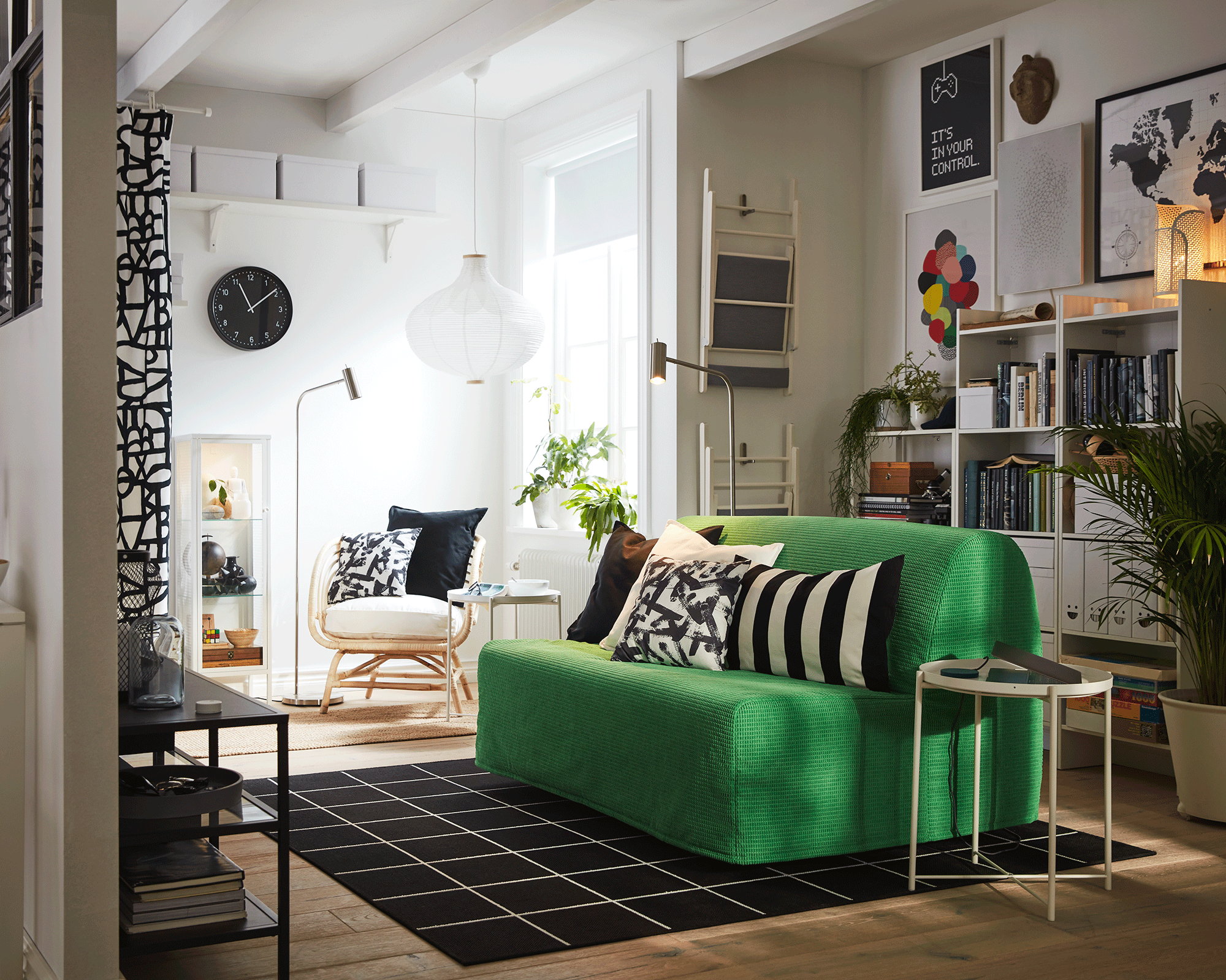 A small lounge with green sofa bed decor, round side table and monochrome area rug