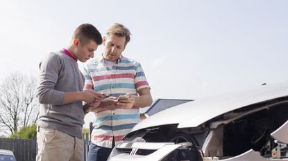 Two men exchange insurance info after a car accident.