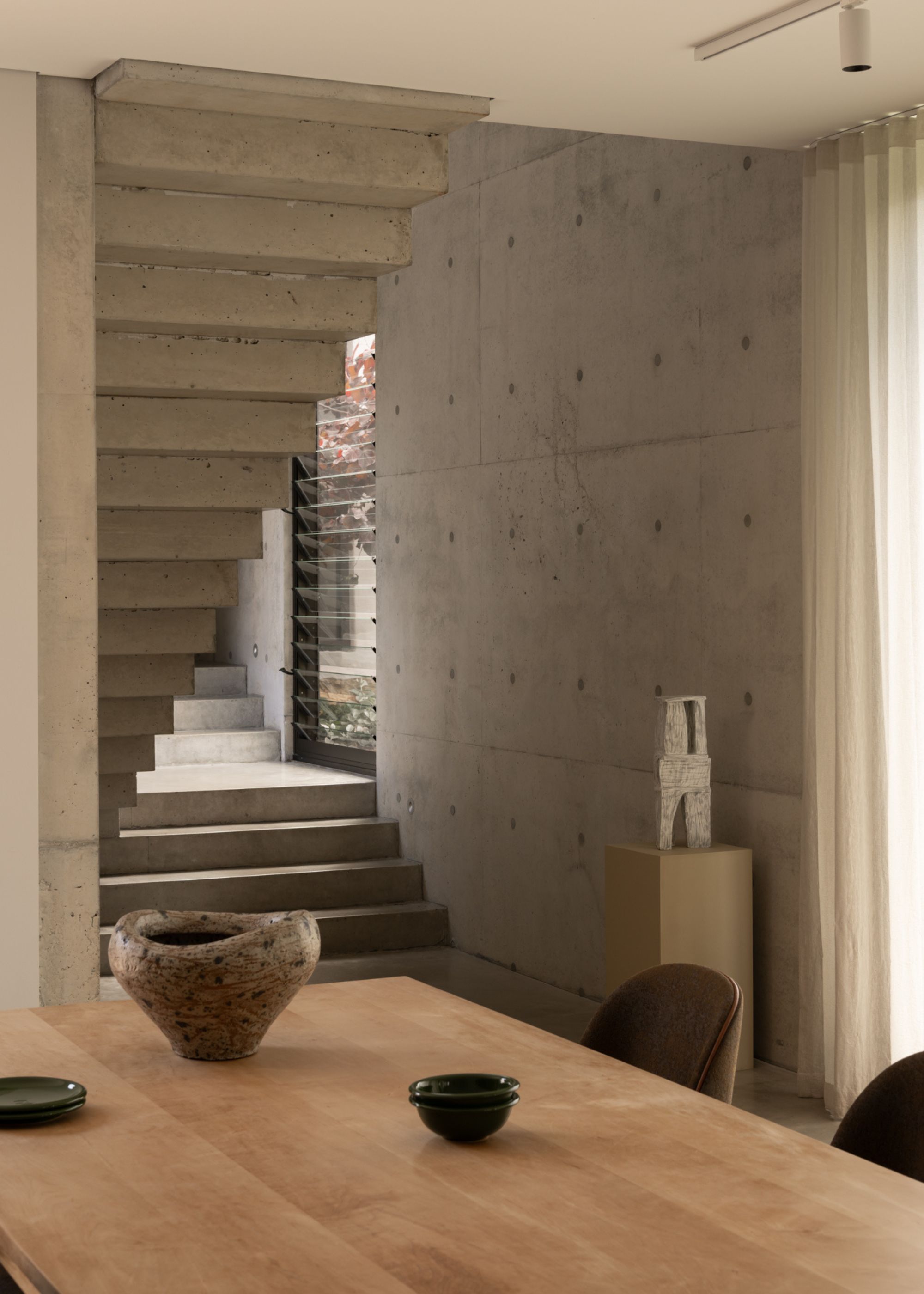 A wood dining table with ceramic bowls in the same room as a concrete staircase