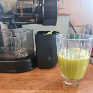 Close up of a Philips Viva Cold Press Masticating Slow Juicer with a glass of celery juice