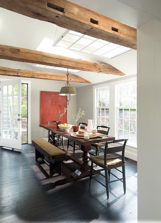 rustic dining room with dark wooden floorboards, pale walls, artwork on wall