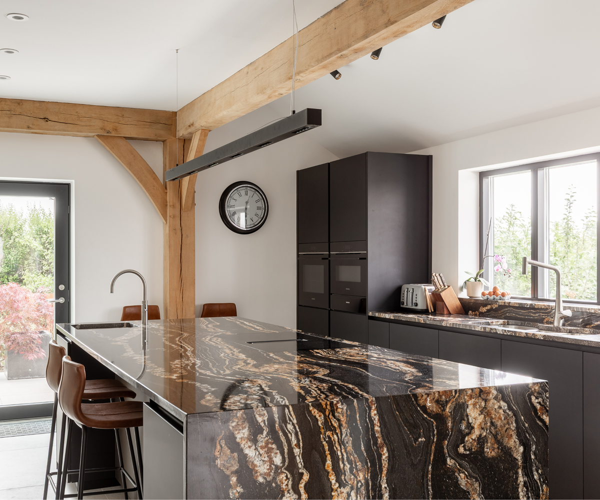 Kitchen with black and gold marble island and black cabinets