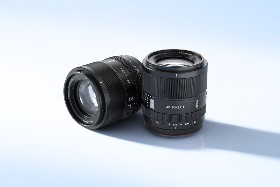 Viltrox AF 75mm F1.8 EVO and AF 90mm F2.2 EVO lenses side by side on a clear sky blue background with strong shadow