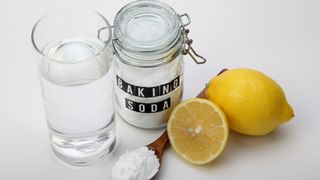 Close-up of baking soda with lemons against white background