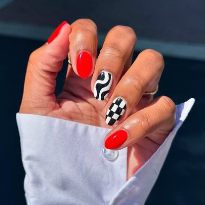 a bright red manicure with two black and white accent nails