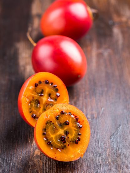 Whole And Sliced Open Tamarillo Tomato Full Of Dark Seeds