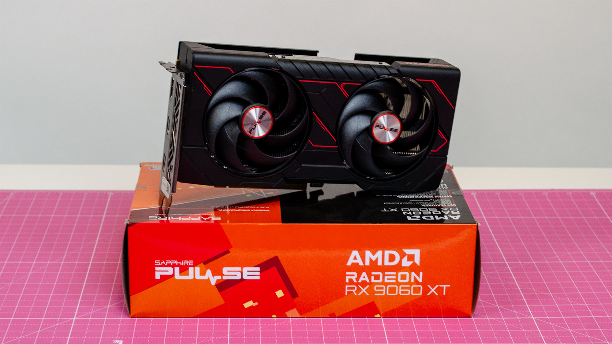 An AMD Radeon RX 9060 XT sitting on its retail packaging on a table