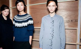 Three models, one with a black duffel coat, one with a blue Fair Isle sweater, and one in a pale blue shirt with ruffles down the front