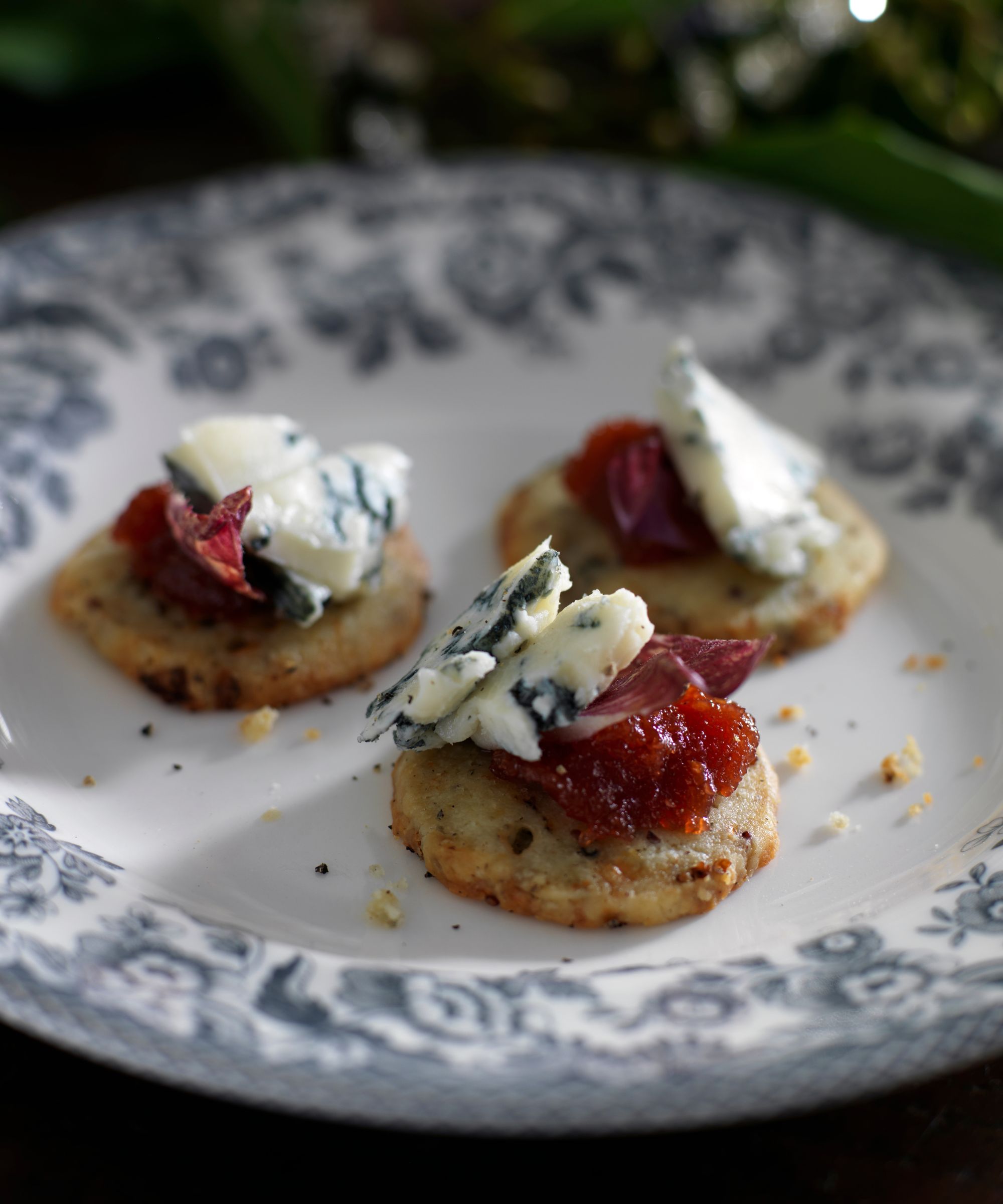 Cheese crackers with gorgonzola and quince jelly on a patterned plate