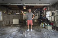 Portrait of senior man standing in garage holding broom 