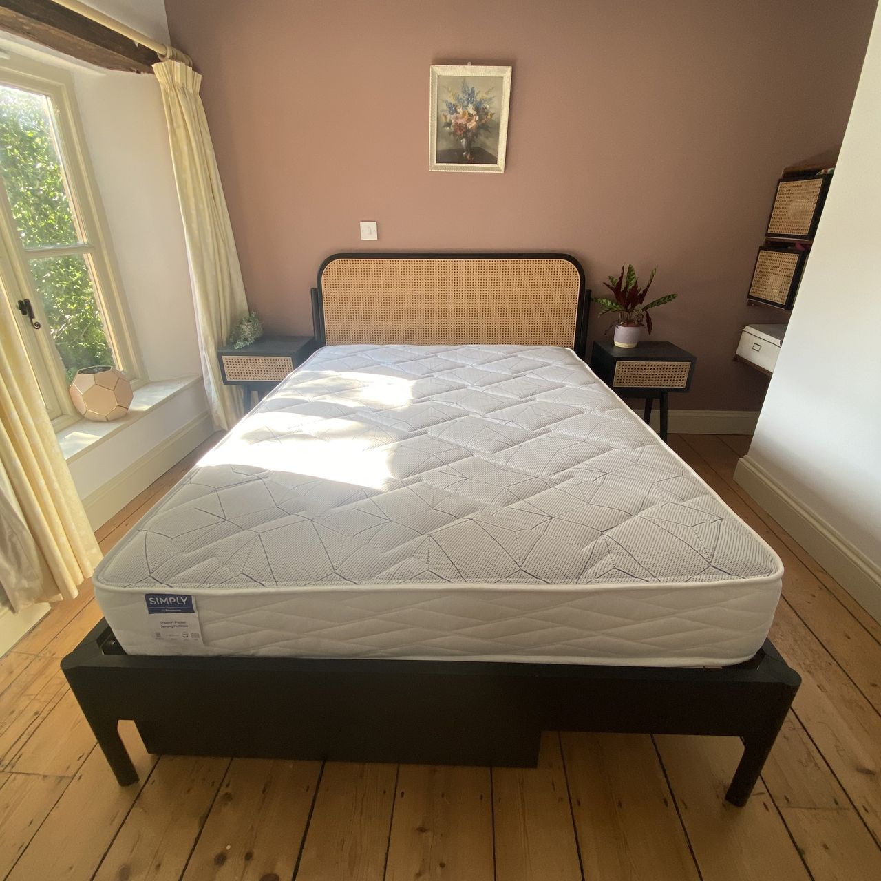 Bensons for Beds Simply Support Pocket Sprung Mattress on a black rattan bed frame in a bedroom.